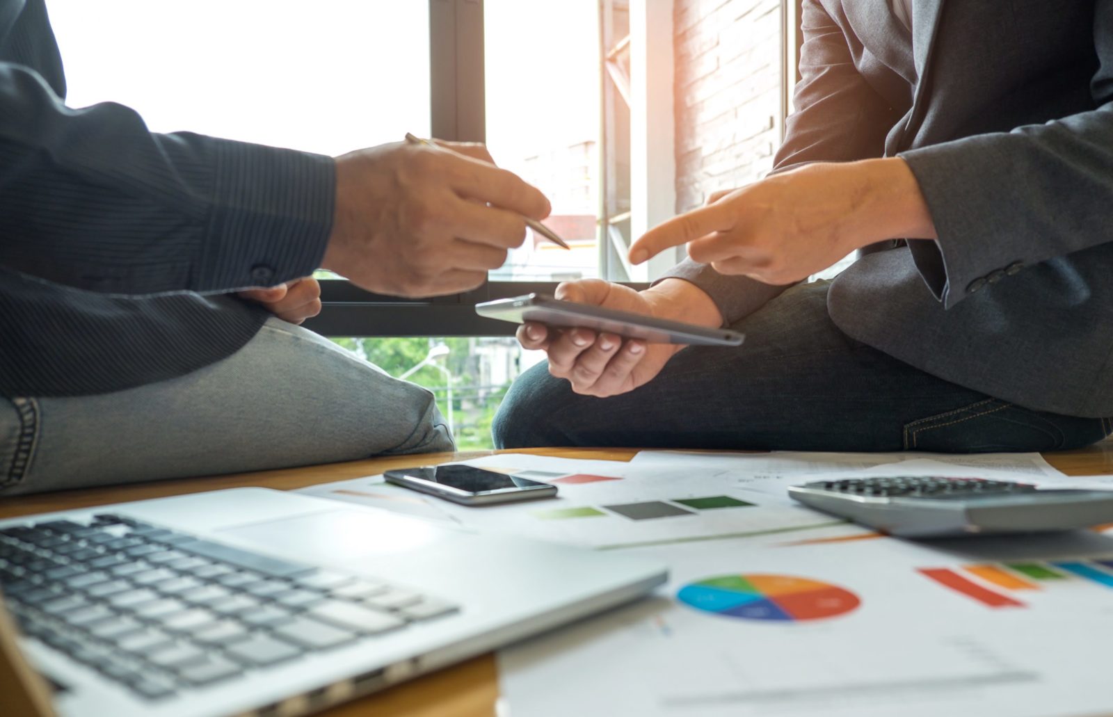 Two professionals reviewing charts and discussing business consulting strategies with a tablet and paperwork for RG Accounting.
