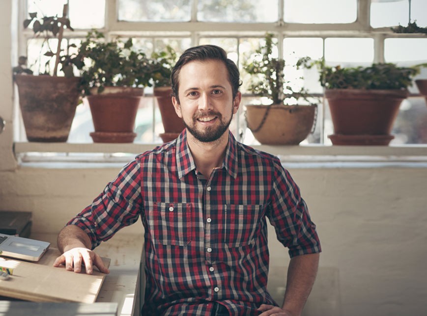 man sitting in front of plants with plaid shirt